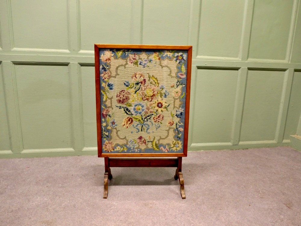 An antique wooden metamorphic fire screen with a framed floral embroidery panel standing on splayed feet. View III