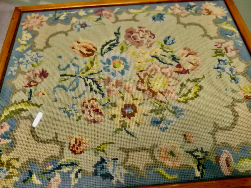An antique wooden metamorphic fire screen with a framed floral embroidery panel standing on splayed feet. View V