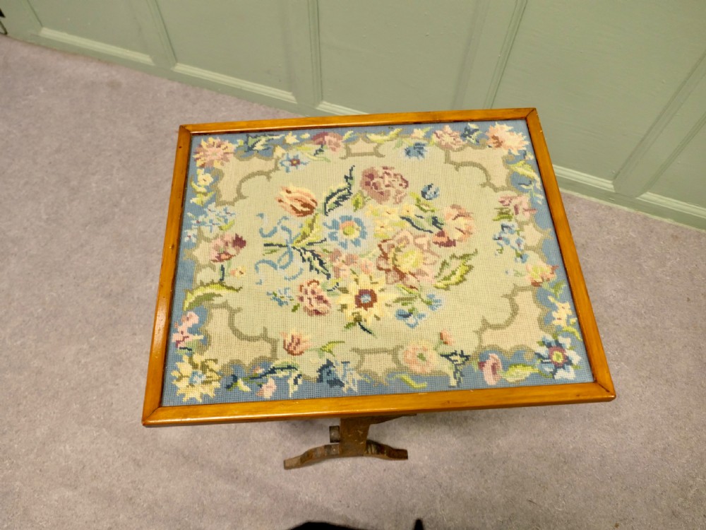 An antique wooden metamorphic fire screen with a framed floral embroidery panel standing on splayed feet. View VI