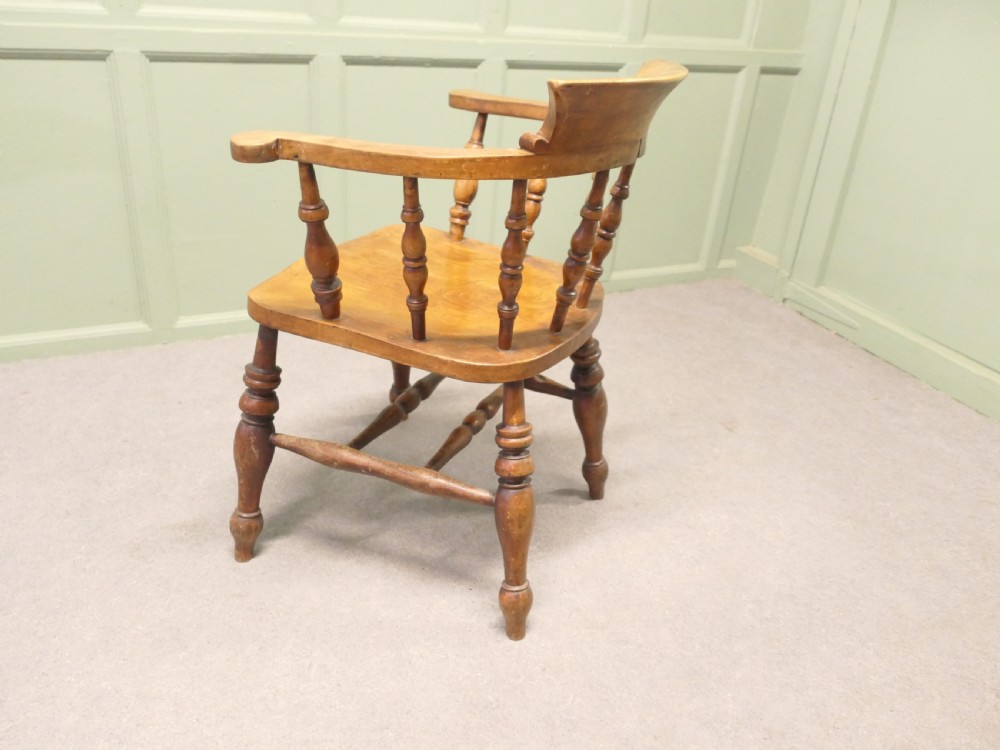 A 19th-century wooden smokers bow desk chair crafted from beech and elm with turned spindles and a shaped saddle seat. View V