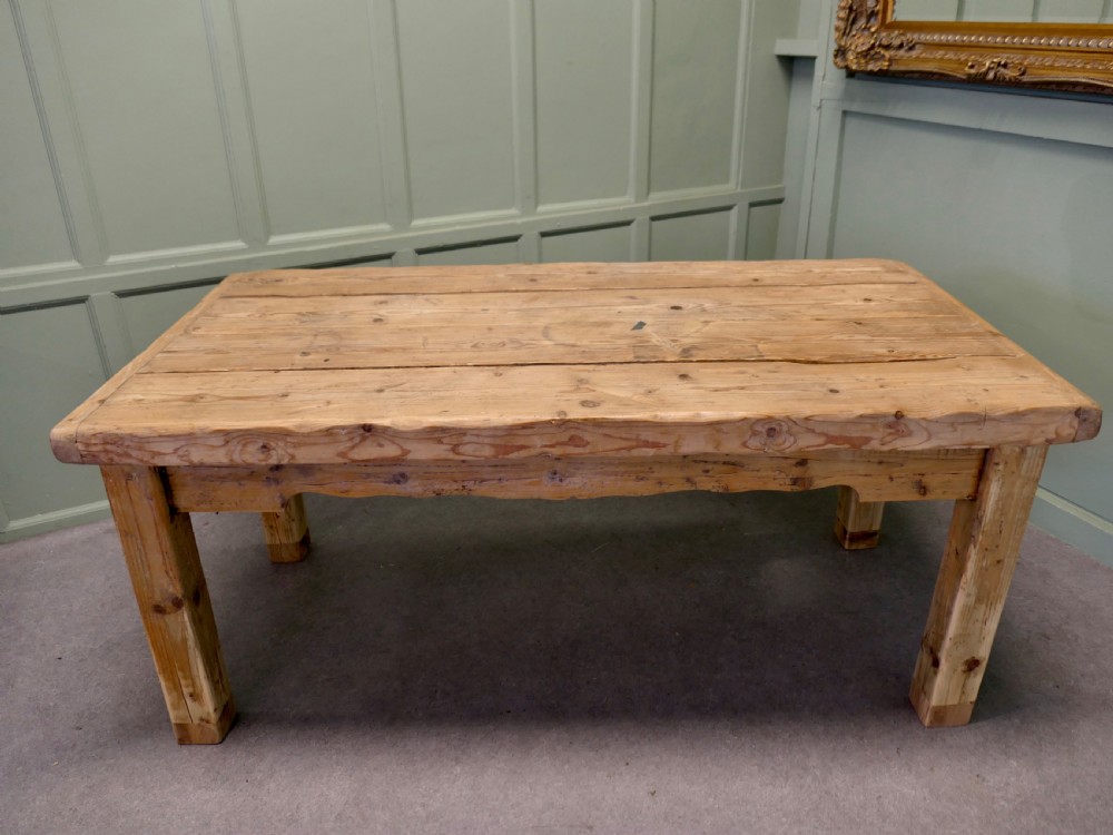 A rustic Victorian scrubbed pine kitchen table featuring a thick plank top and solid square-section legs.