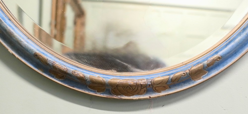 An Art Deco oval wall mirror featuring a pale blue painted frame with carved gilt leaf motifs enclosing an oval glass mirror plate. View IV