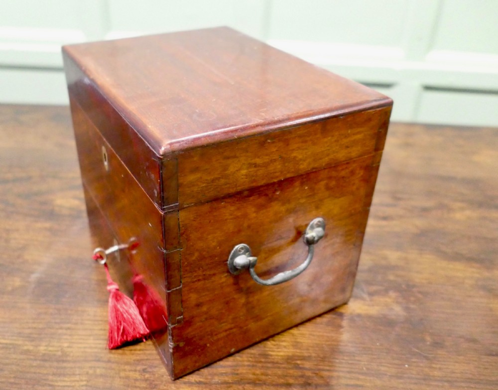 An open antique mahogany apothecary chest featuring velvet-lined compartments filled with glass bottles and a lower drawer containing scales. View II
