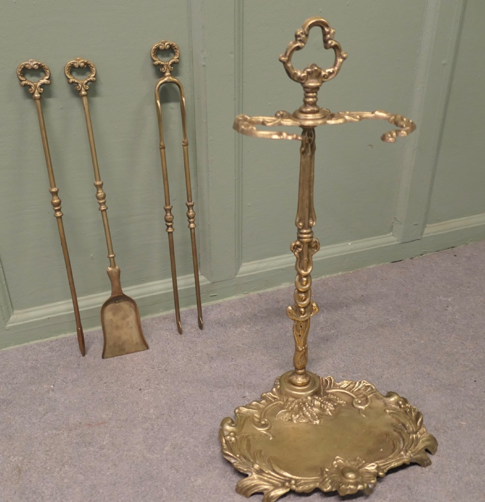 A solid brass Rococo style fireside companion set featuring an ornate scrollwork stand holding a shovel, poker, and tongs. View IV
