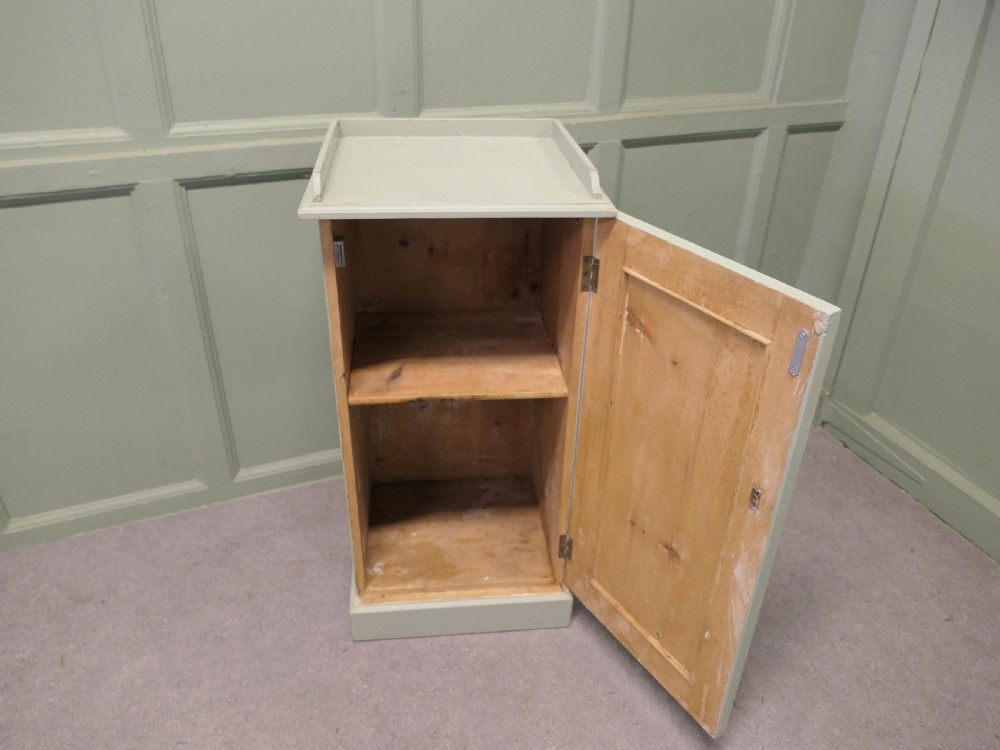 A painted light grey pine bedside cupboard featuring a gallery top rim, a single panelled door with a dark turned knob, and a solid plinth base. View IV