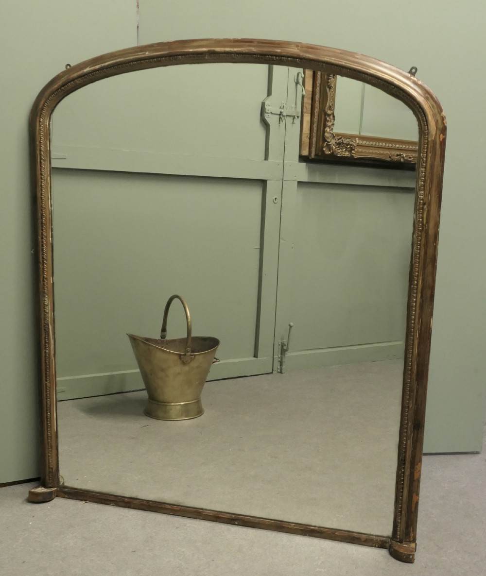 A large Victorian arched overmantel mirror featuring a distressed giltwood frame with subtle beaded moulding and a flat base. View III