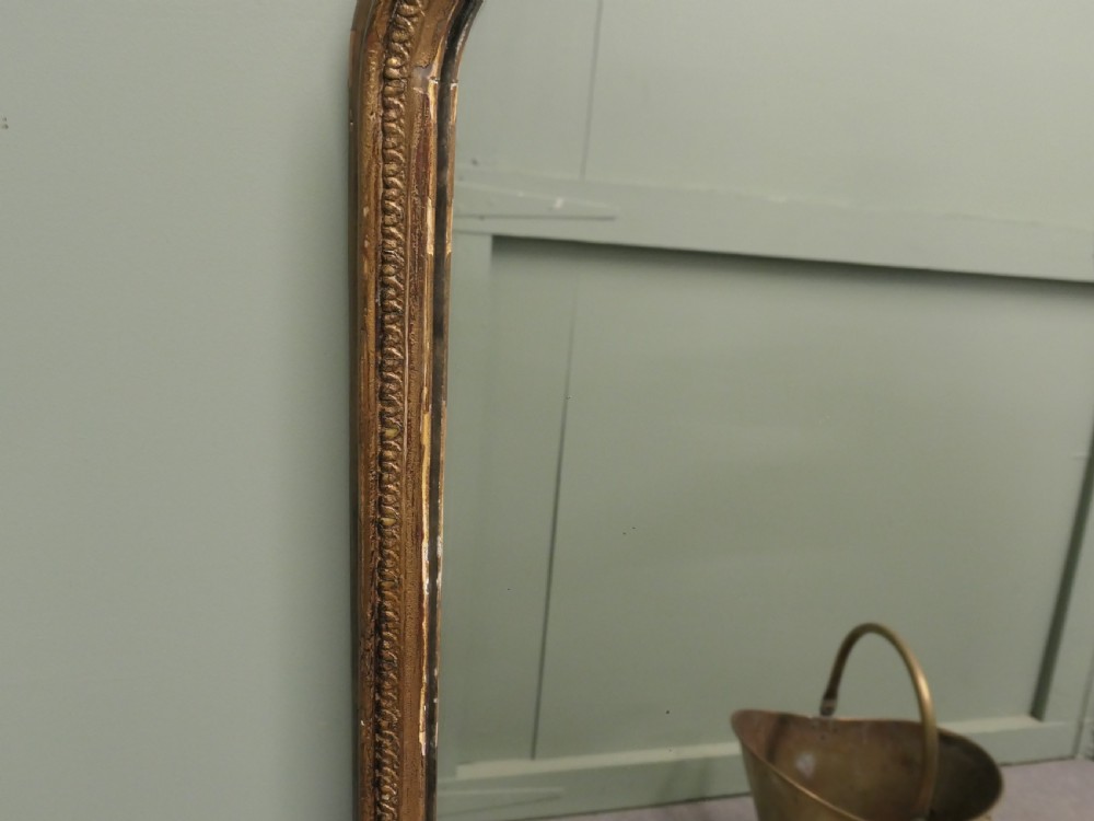A large Victorian arched overmantel mirror featuring a distressed giltwood frame with subtle beaded moulding and a flat base. View IV