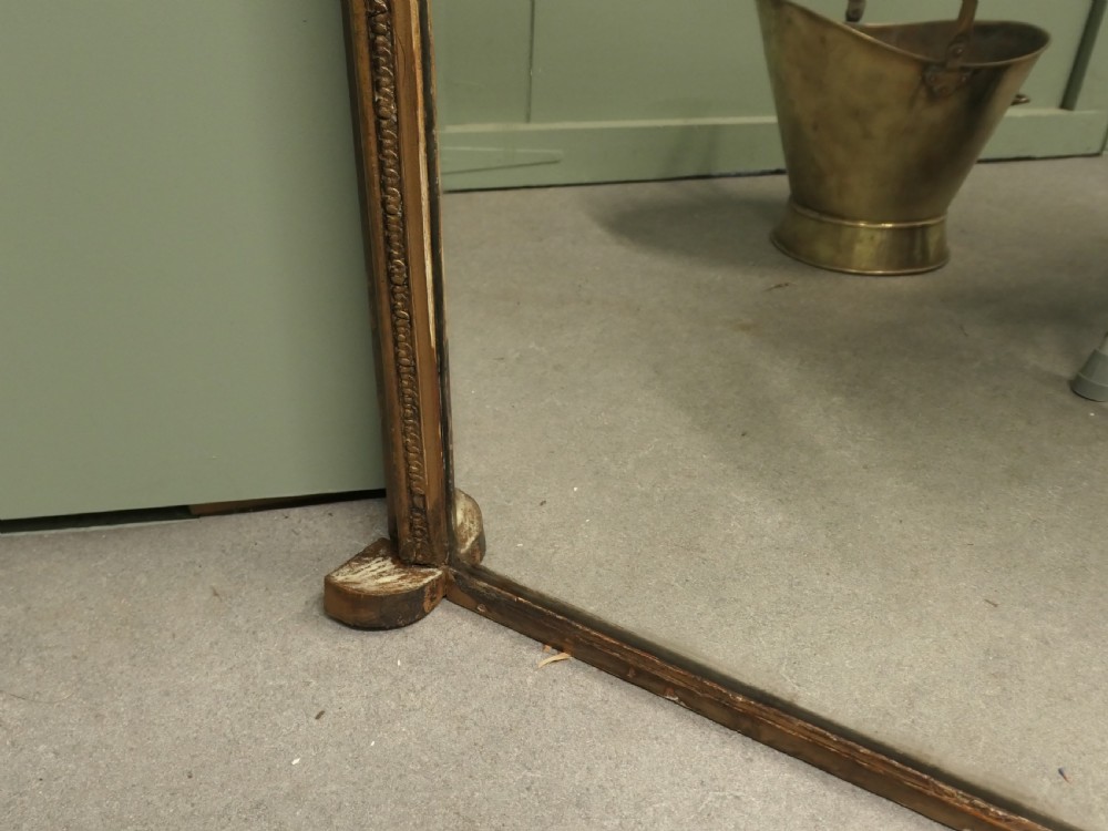 A large Victorian arched overmantel mirror featuring a distressed giltwood frame with subtle beaded moulding and a flat base. View V