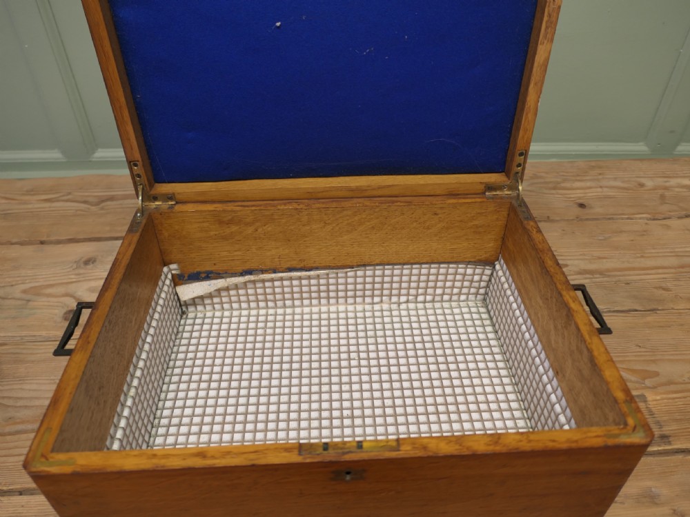 A rectangular warm brown Victorian oak presentation box featuring a hinged lid with a central brass monogrammed plaque and a keyhole on the front face. View V