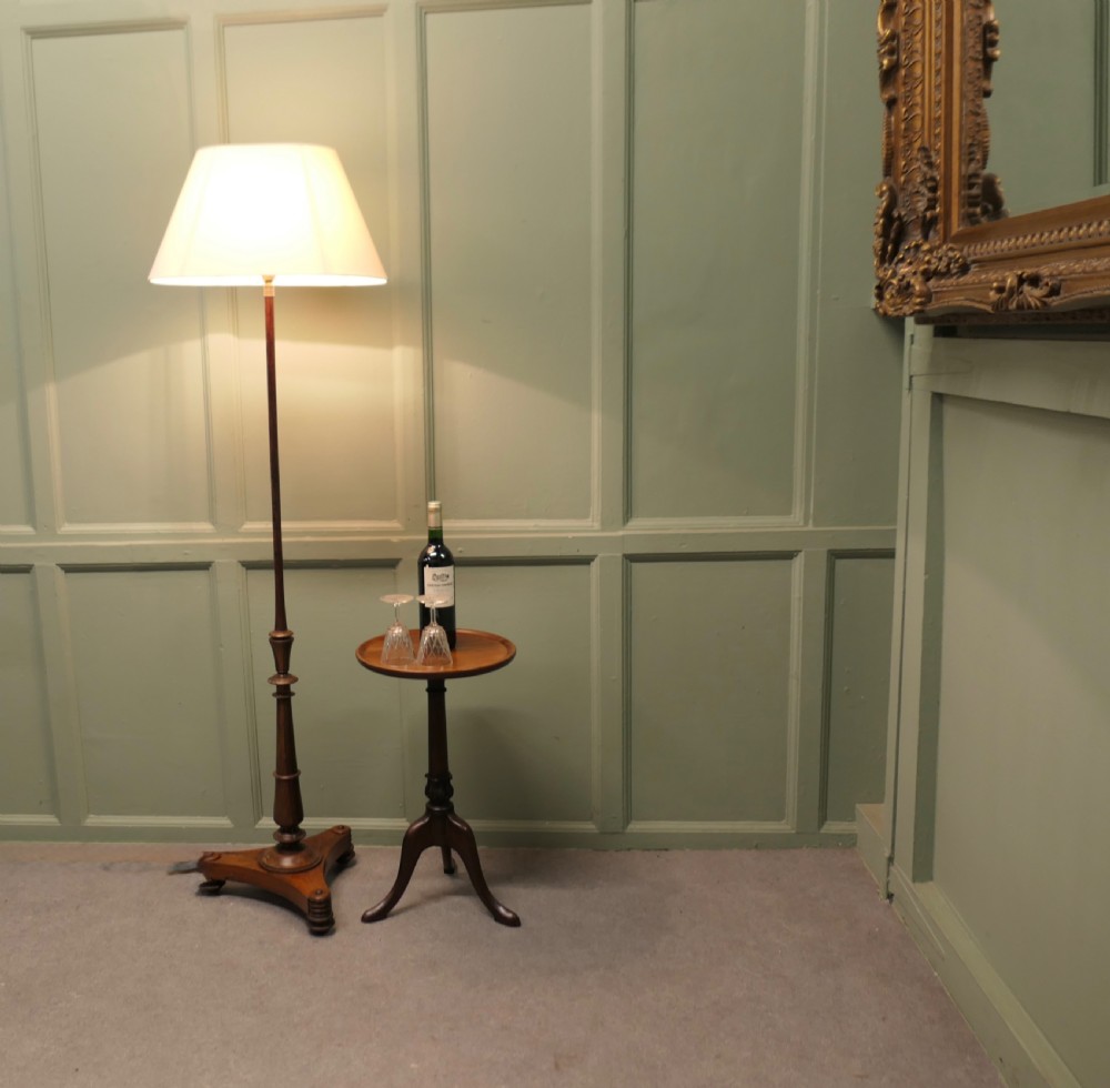 A slender turned wooden standard floor lamp featuring a triform base on rounded feet and topped with a tapered cream fabric shade. View III