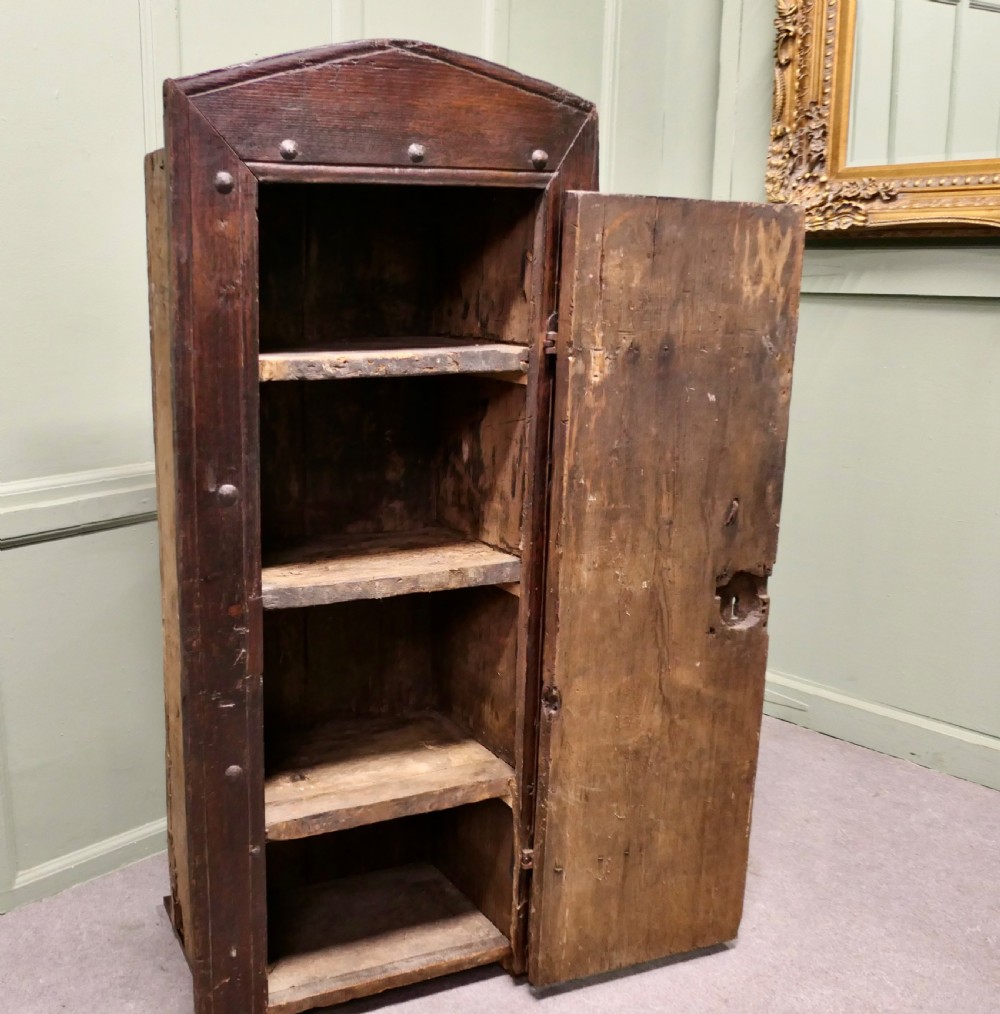 A narrow dark oak alcove cupboard featuring an arched top frame, iron studs, and hand-forged wrought iron hinges. View VI
