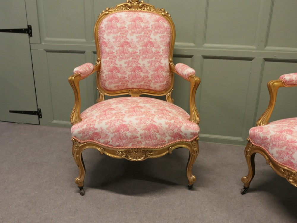 A pair of 19th-century French giltwood salon armchairs featuring carved floral frames and pink pattern fabric upholstery. View II