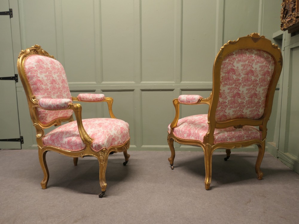 A pair of 19th-century French giltwood salon armchairs featuring carved floral frames and pink pattern fabric upholstery. View III