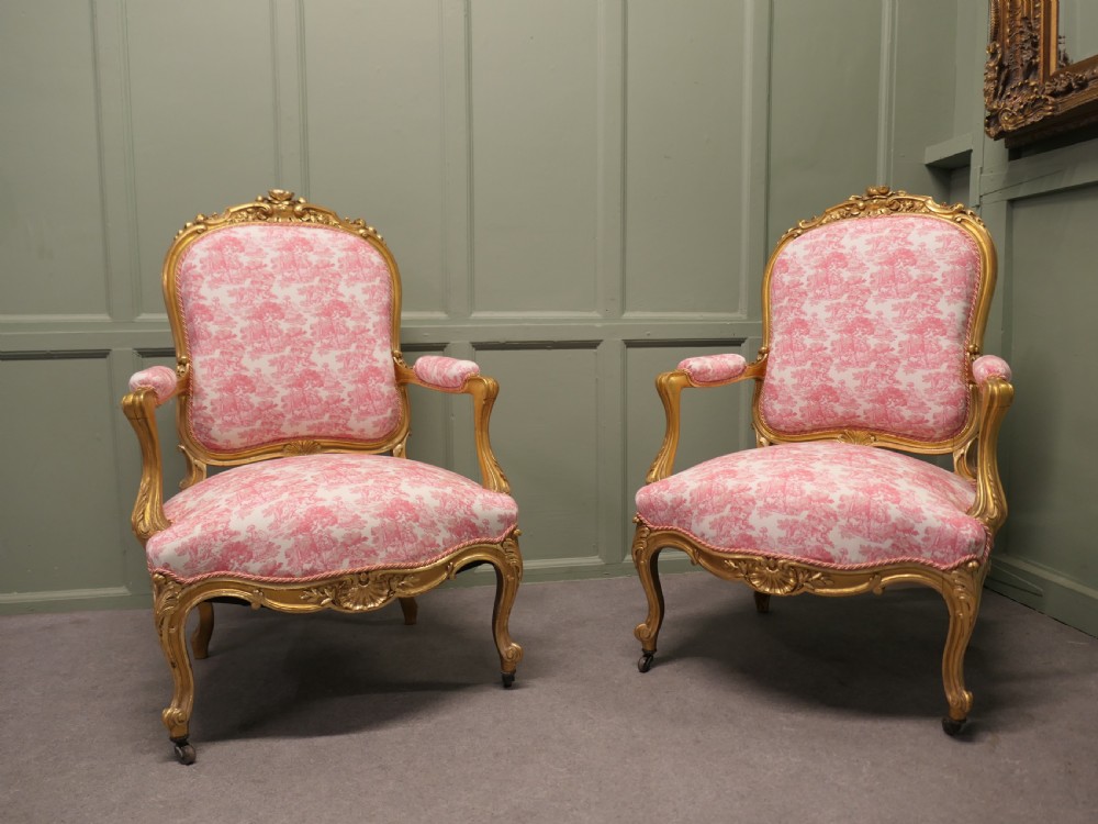 A pair of 19th-century French giltwood salon armchairs featuring carved floral frames and pink pattern fabric upholstery. View IV