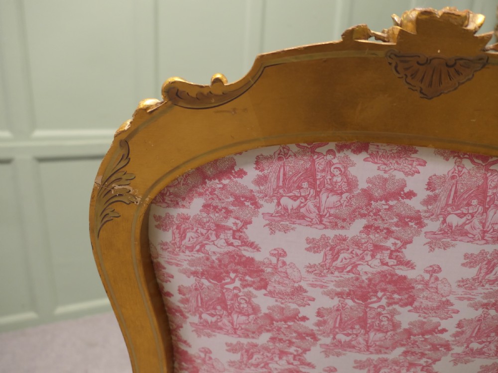 A pair of 19th-century French giltwood salon armchairs featuring carved floral frames and pink pattern fabric upholstery. View V