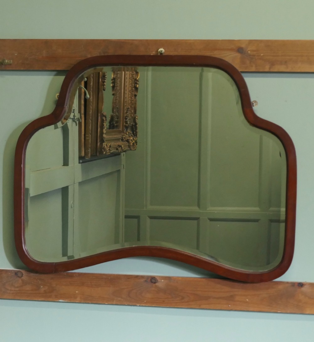 An Art Deco wall mirror featuring a contoured, shaped walnut wood frame surrounding a flat glass plate. View II
