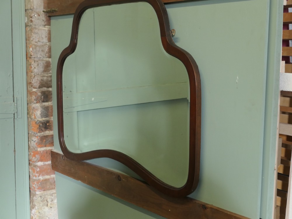An Art Deco wall mirror featuring a contoured, shaped walnut wood frame surrounding a flat glass plate. View III