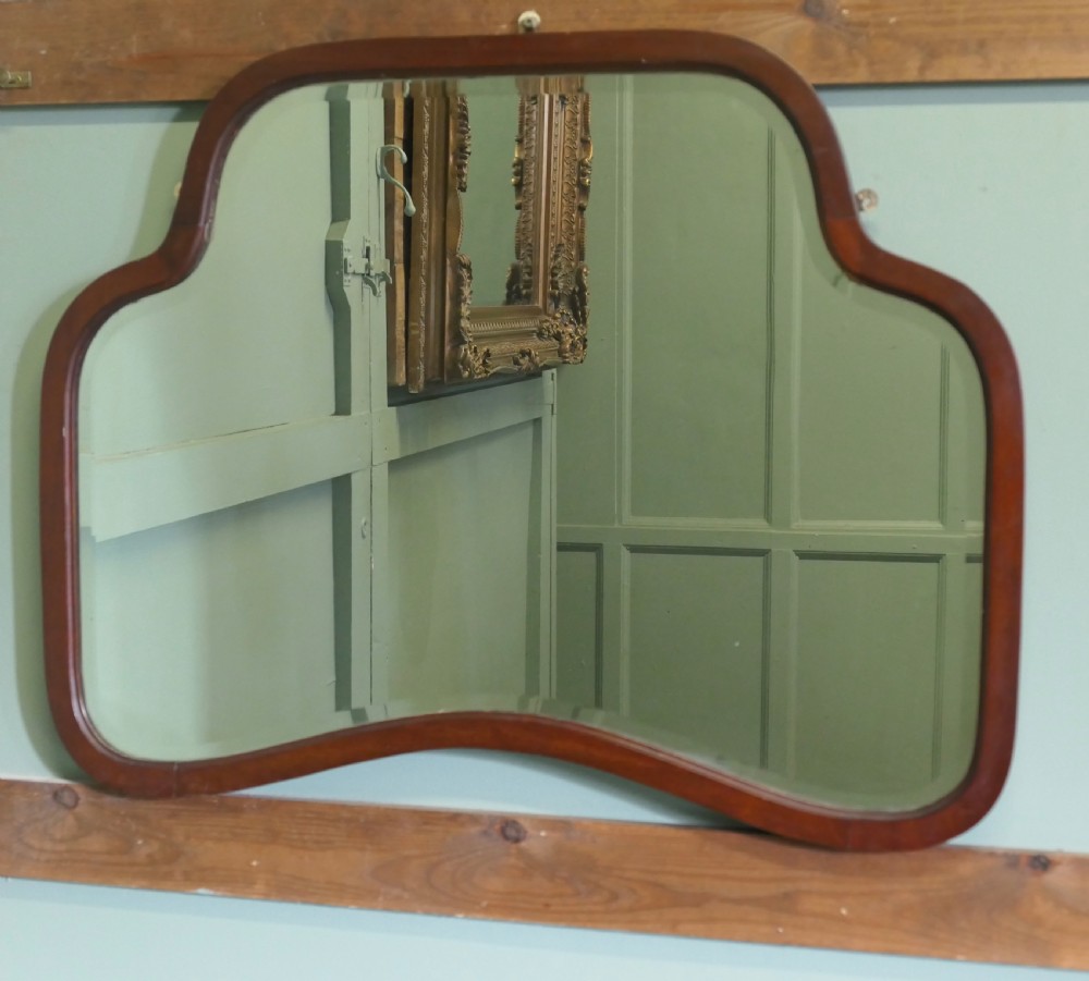 An Art Deco wall mirror featuring a contoured, shaped walnut wood frame surrounding a flat glass plate. View IV
