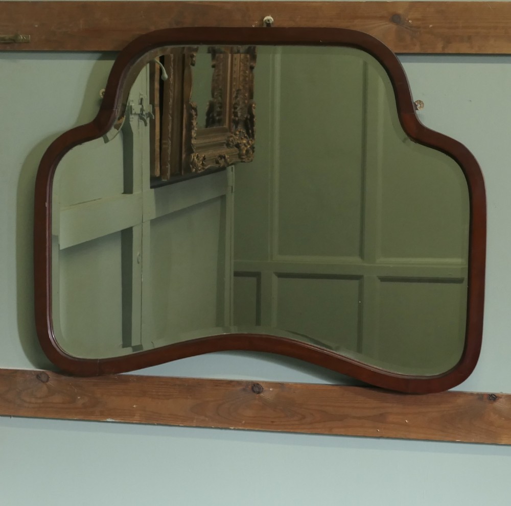 An Art Deco wall mirror featuring a contoured, shaped walnut wood frame surrounding a flat glass plate. View V