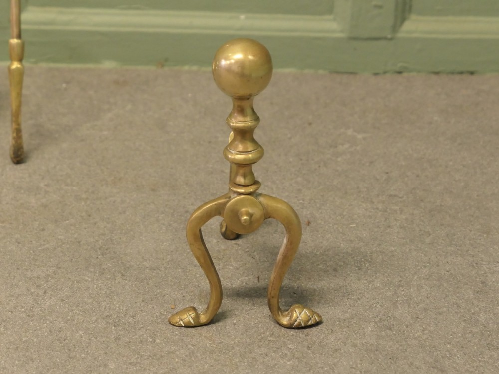 A solid brass fireplace tool set including a shovel, tongs, and poker resting horizontally on matching brass rests. View III