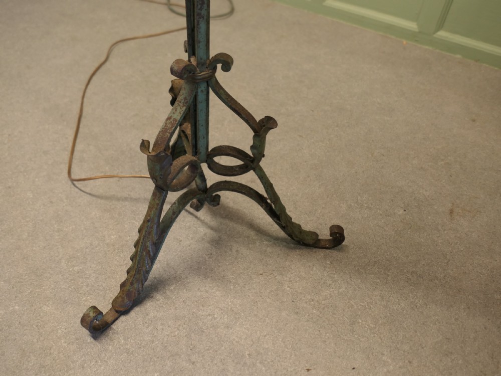 A tall wrought iron floor lamp featuring decorative scrollwork at the stem and base, finished with a cream fabric fringed shade. View II