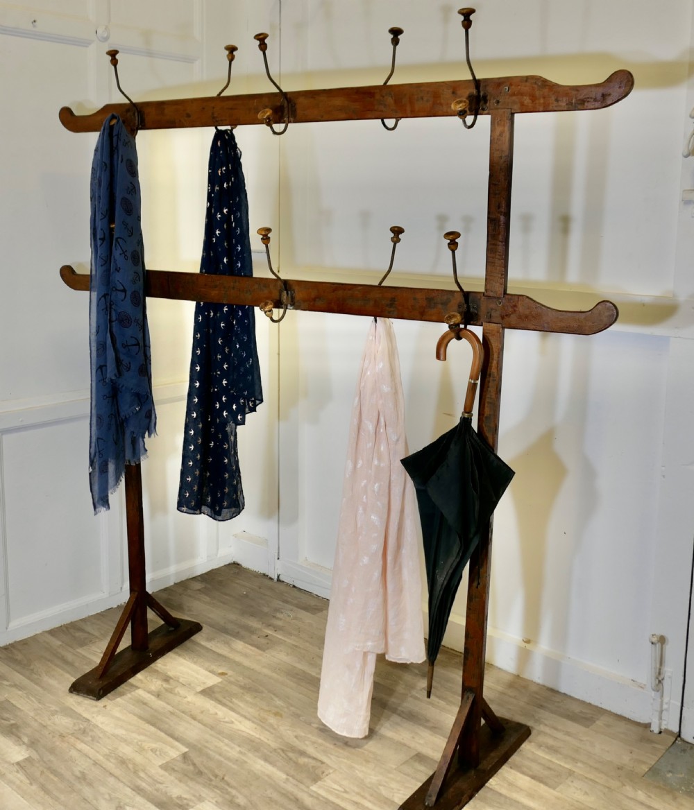 A freestanding double-sided French Arts and Crafts coat rack crafted from golden pine with two horizontal bars holding metal and wood pegs. View VI
