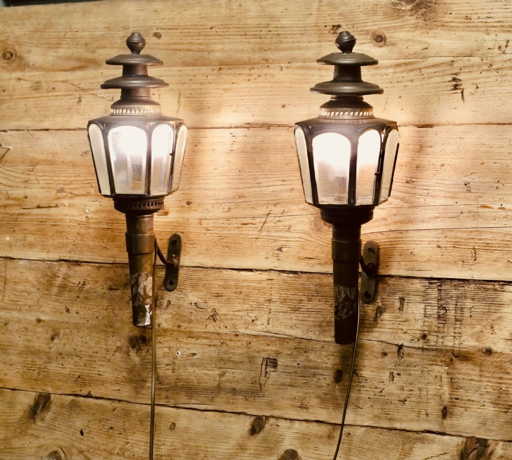 A pair of wall-mounted French brass carriage lanterns featuring tiered chimney tops and glazed glass panels.