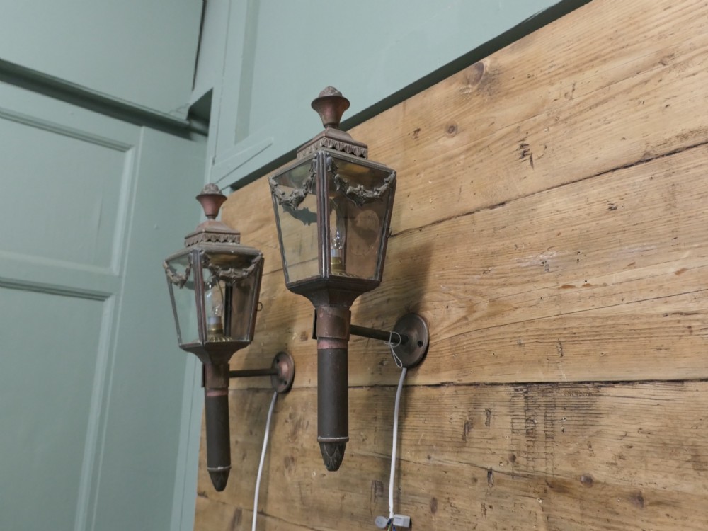 A pair of French Empire style aged brass carriage lanterns with glass panels, leaf swags, and urn finials mounted on cylindrical stems. View VI