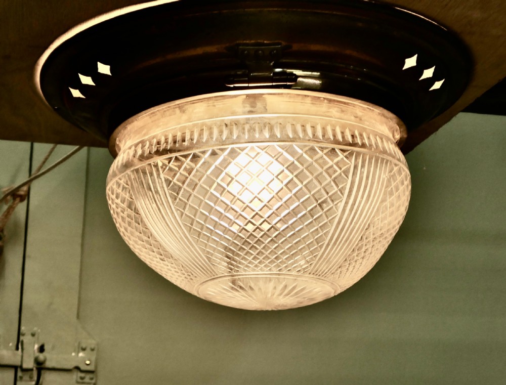 An Art Deco flush mount ceiling light featuring a hemispherical cut glass shade with geometric diamond patterns set into a dark metal collar with diamond-shaped perforations. View V