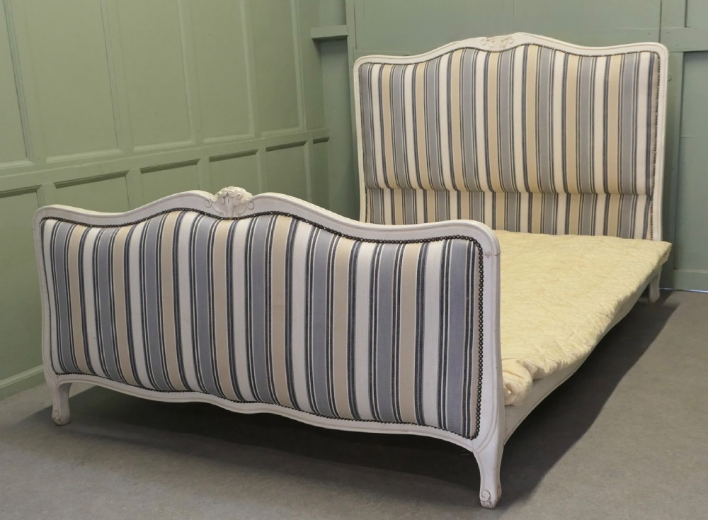 A French Louis XV style double bed featuring a cream painted carved wooden frame and grey striped upholstered headboard and footboard.