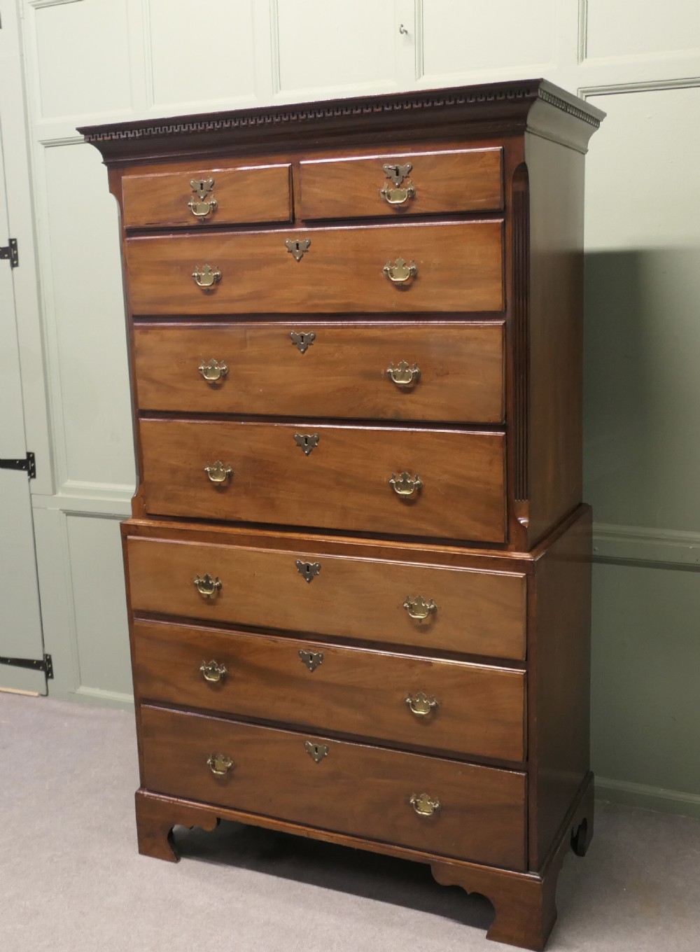 An early Victorian mahogany chest on chest featuring eight drawers with brass bail handles, fluted corner details, and bracket feet.
