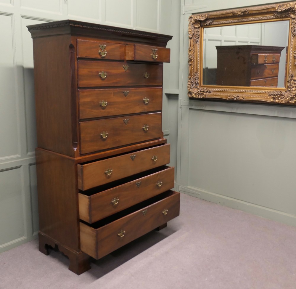 An early Victorian mahogany chest on chest featuring eight drawers with brass bail handles, fluted corner details, and bracket feet. View V
