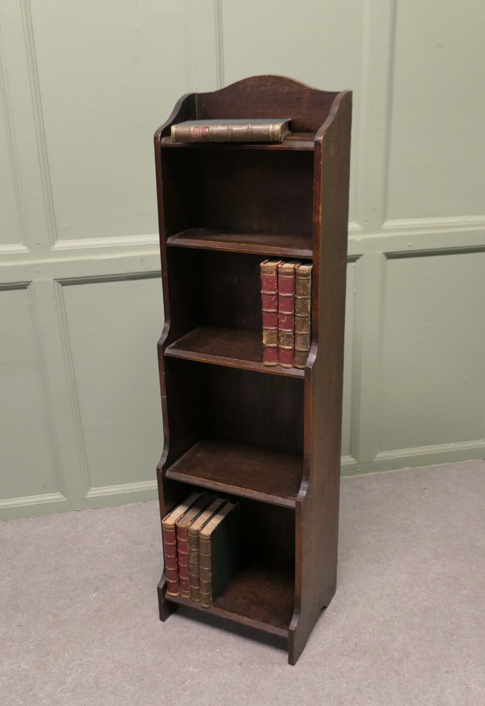 A tall, narrow dark oak bookcase featuring five open tiers and stepped, shaped side panels. View VI