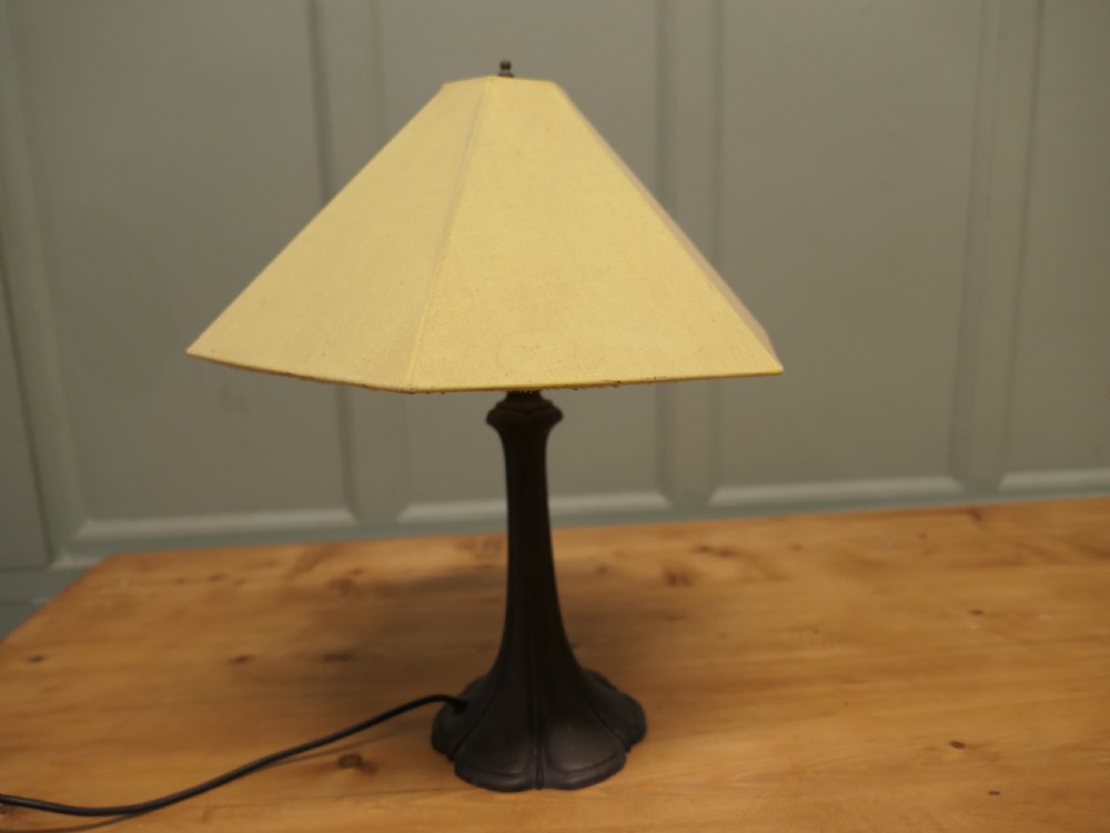 An Art Nouveau table lamp featuring a flared dark metal spelter base and a cream pyramidal fabric shade. View II