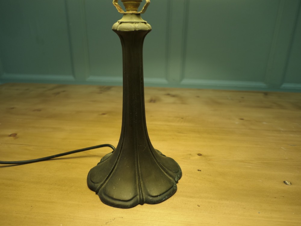 An Art Nouveau table lamp featuring a flared dark metal spelter base and a cream pyramidal fabric shade. View IV