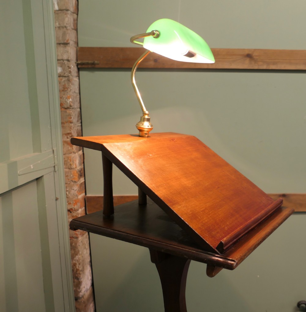 A dark wooden standing lectern with a slanted book rest, a slender curved stem, and an attached brass lamp holding a green glass shade. View V