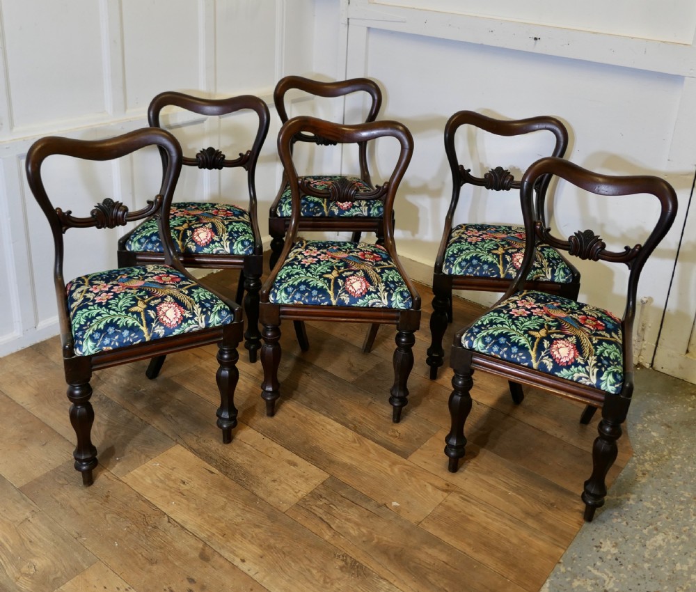 A set of six Victorian mahogany balloon-back dining chairs with carved mid-rails and blue floral patterned velvet seats.