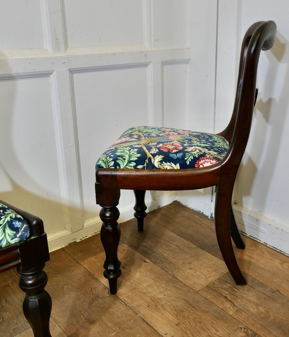 A set of six Victorian mahogany balloon-back dining chairs with carved mid-rails and blue floral patterned velvet seats. View VI