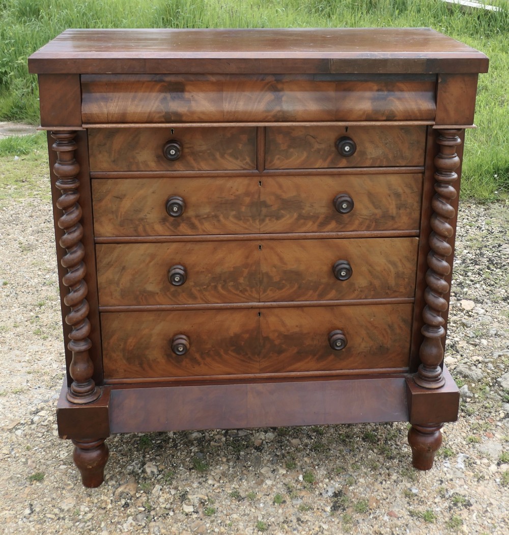 A Victorian flame mahogany Scotch chest of drawers with carved barley twist side columns and turned wooden knobs. View III