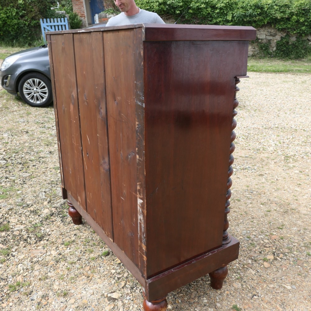 A Victorian flame mahogany Scotch chest of drawers with carved barley twist side columns and turned wooden knobs. View VI