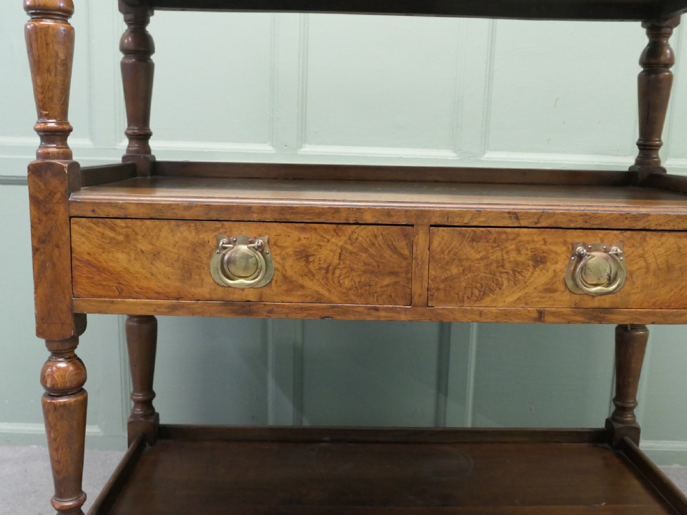 A Victorian oak three-tier buffet featuring turned upright columns, corner finials, two drawers with brass drop handles, and brass castors. View III