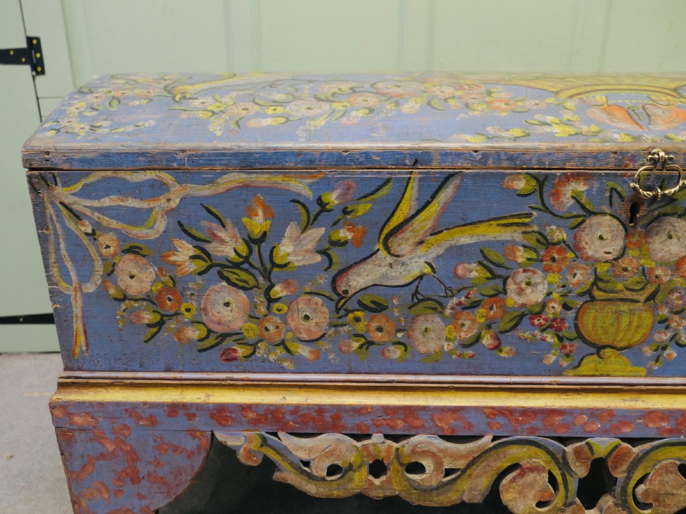 A large blue hand-painted wooden marriage chest decorated with floral motifs, birds, and an openwork scroll-carved base apron. View III