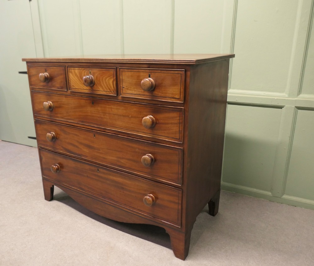 A late 18th-century Georgian mahogany chest of drawers featuring three small top drawers above three full-width drawers with turned wooden handles and a curved lower apron. View VI