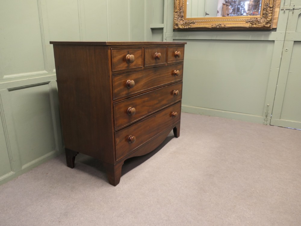 A late 18th-century Georgian mahogany chest of drawers featuring three small top drawers above three full-width drawers with turned wooden handles and a curved lower apron. View VII