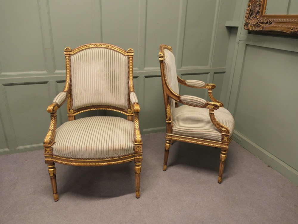 A pair of French style open armchairs featuring carved giltwood frames, fluted legs, and striped sage green and cream fabric upholstery. View II