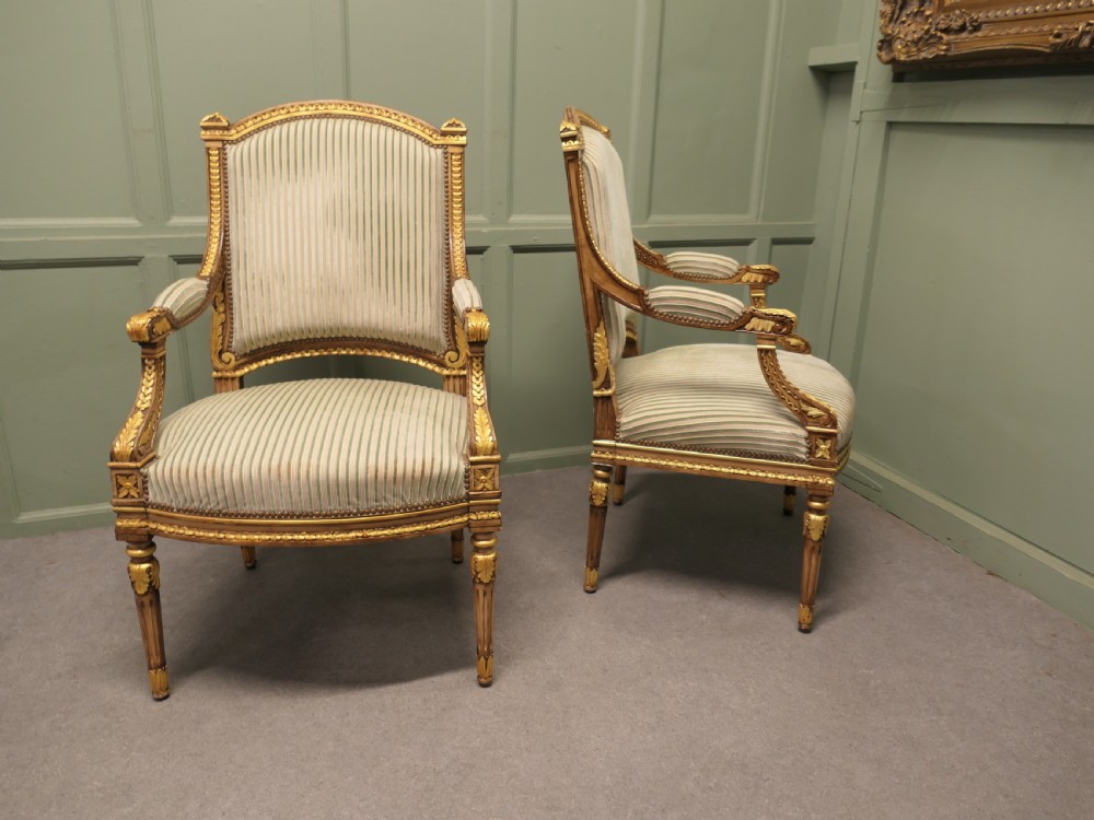 A pair of French style open armchairs featuring carved giltwood frames, fluted legs, and striped sage green and cream fabric upholstery. View III