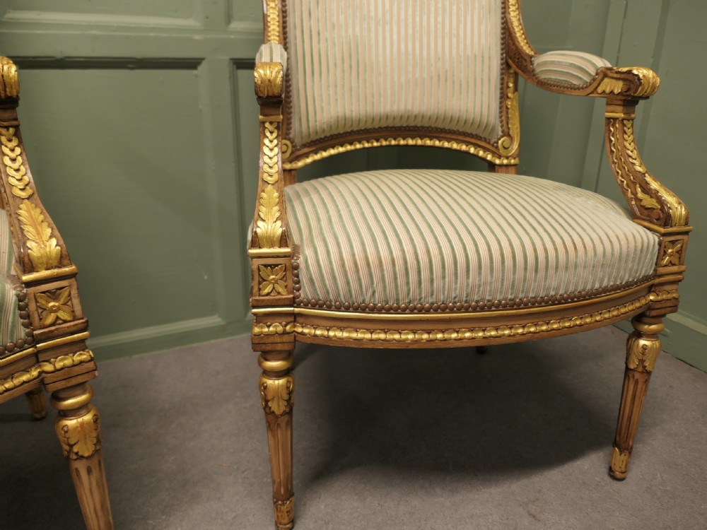 A pair of French style open armchairs featuring carved giltwood frames, fluted legs, and striped sage green and cream fabric upholstery. View IV