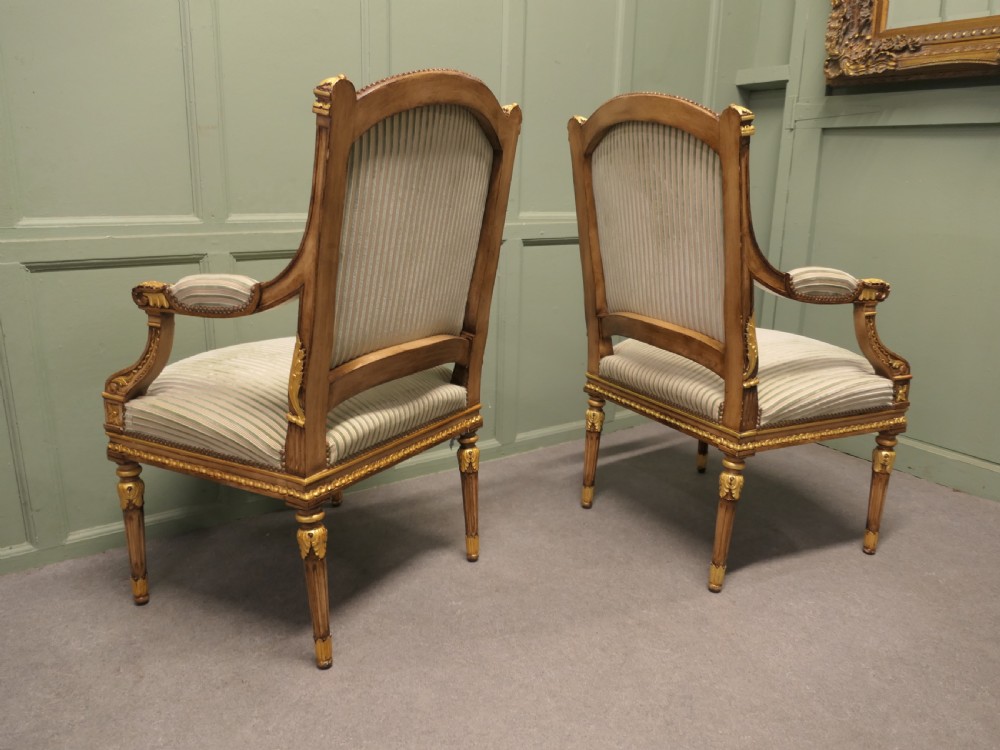 A pair of French style open armchairs featuring carved giltwood frames, fluted legs, and striped sage green and cream fabric upholstery. View V