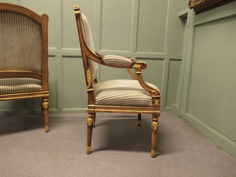 A pair of French style open armchairs featuring carved giltwood frames, fluted legs, and striped sage green and cream fabric upholstery. View VI