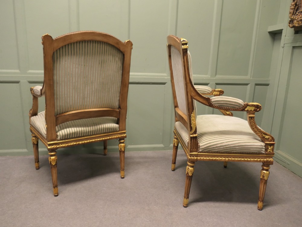 A pair of French style open armchairs featuring carved giltwood frames, fluted legs, and striped sage green and cream fabric upholstery. View VII